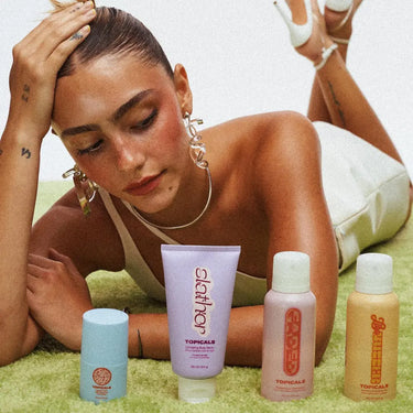 Skincare products for dark spots displayed in front of a woman lying on a green rug, featuring various Topicals products